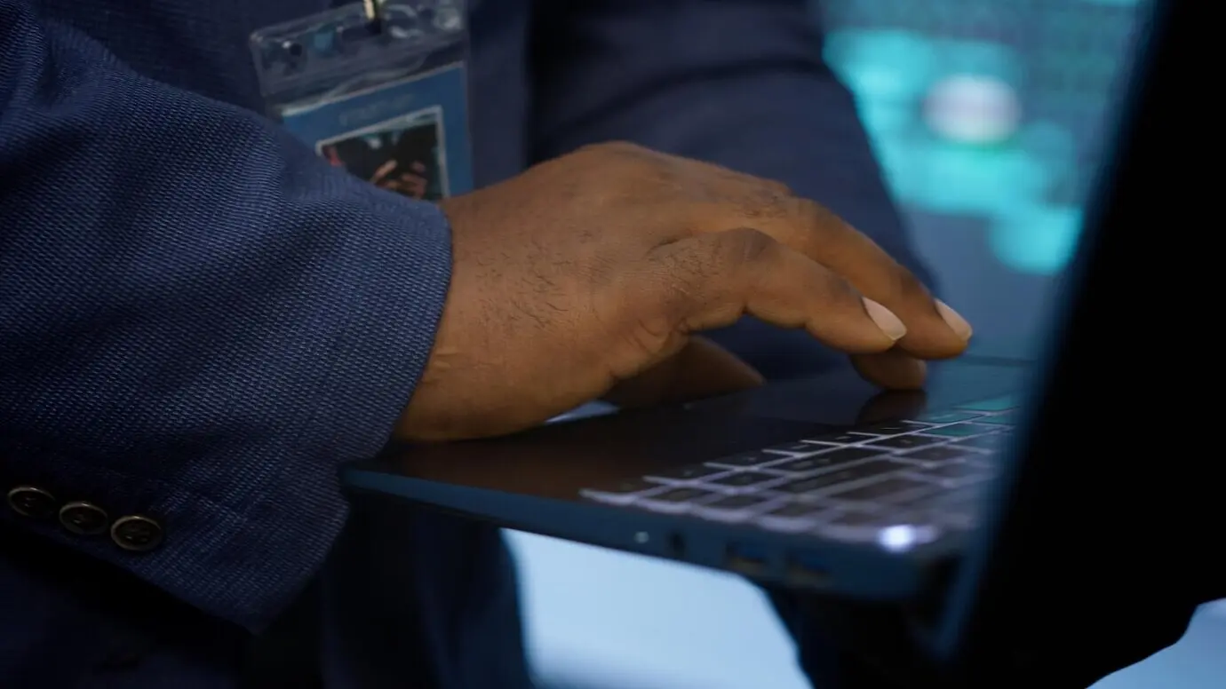 Сверхкрупный план мужчины, работающего за ноутбуком в дата-центре.